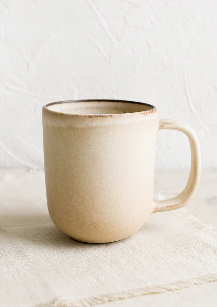 A ceramic coffee mug in matte tan glaze.