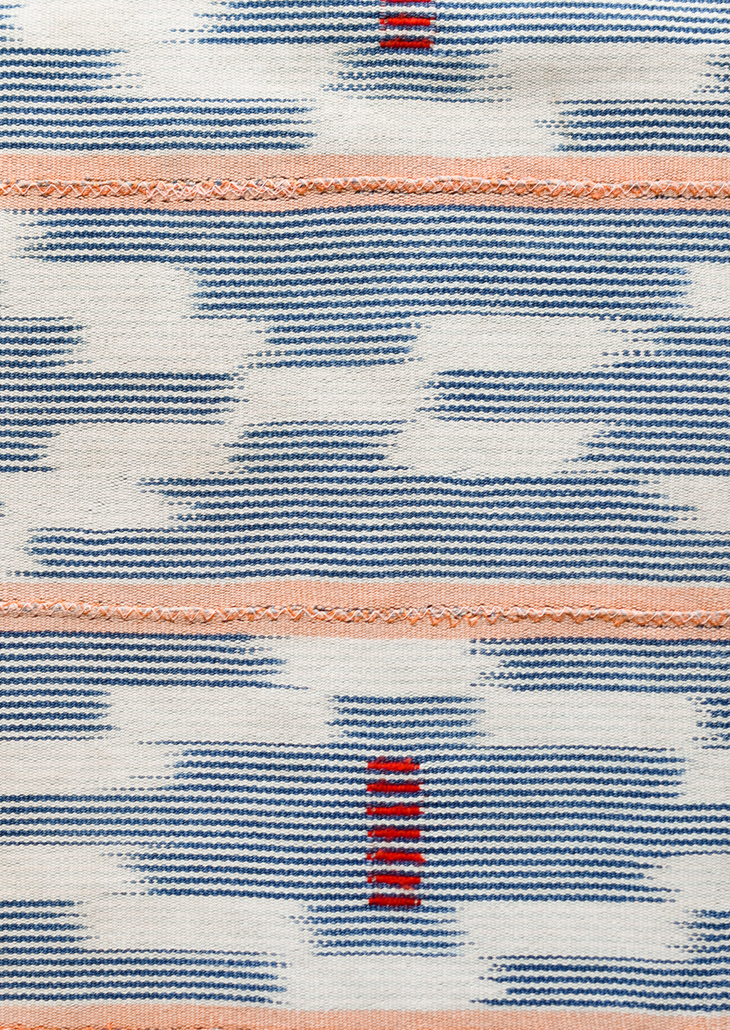 2: A throw pillow made from indigo baule fabric with peach stripes.