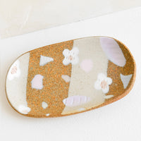 1: A small oval ceramic tray with pastel flower and terrazzo pattern.