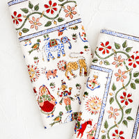 1: Pair of folded cotton dinner napkins in white with multicolor carnival print