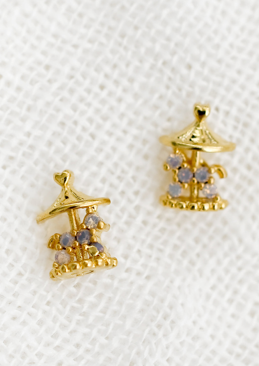 1: A pair of gold stud earrings in shape of carousel.