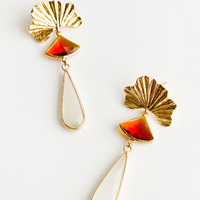 1: Dangling earrings featuring red triangle and ivory teardrop crystals hanging from a yellow gold shell charm.