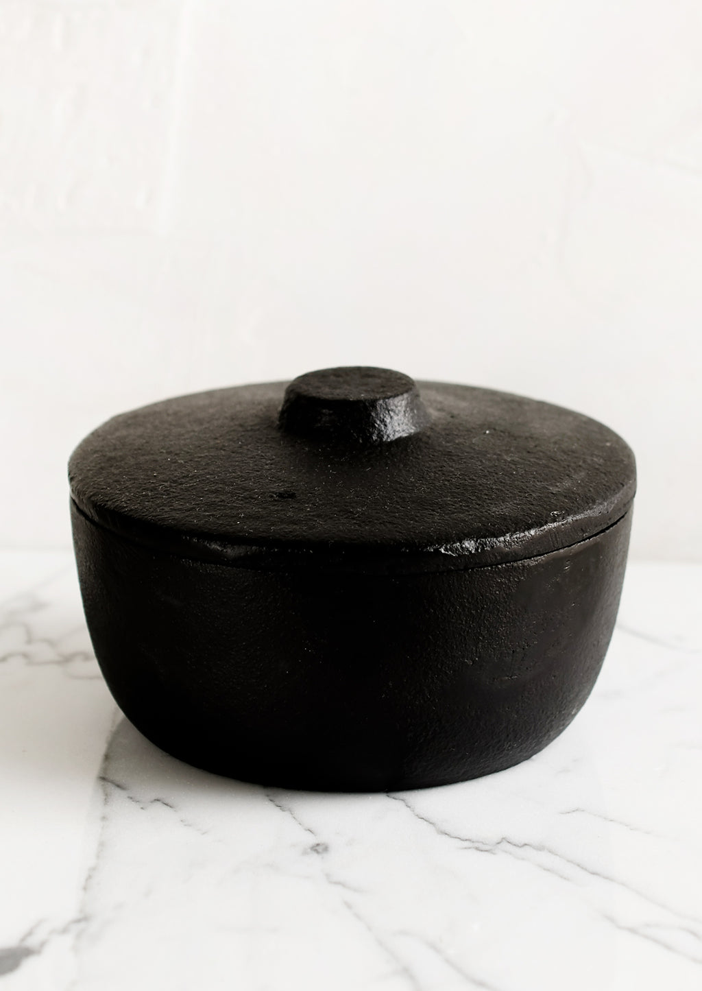 1: A black cast iron lidded storage jar.