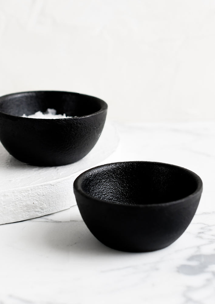 Two small cast iron pinch bowls, one holding salt.