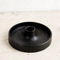 2: A taper candle holder in black cast iron with a wide base.