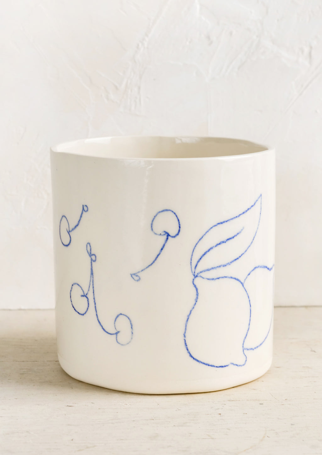 1: An ivory ceramic planter with fruit line drawings in blue.