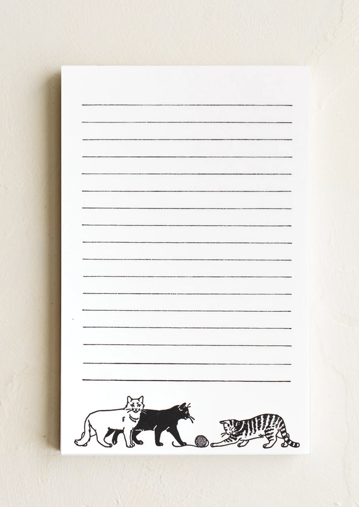 A white notepad with black lines and cat print with yarn.