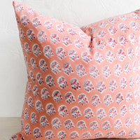 3: A square block printed pillow with a pink, grey, and red floral design.