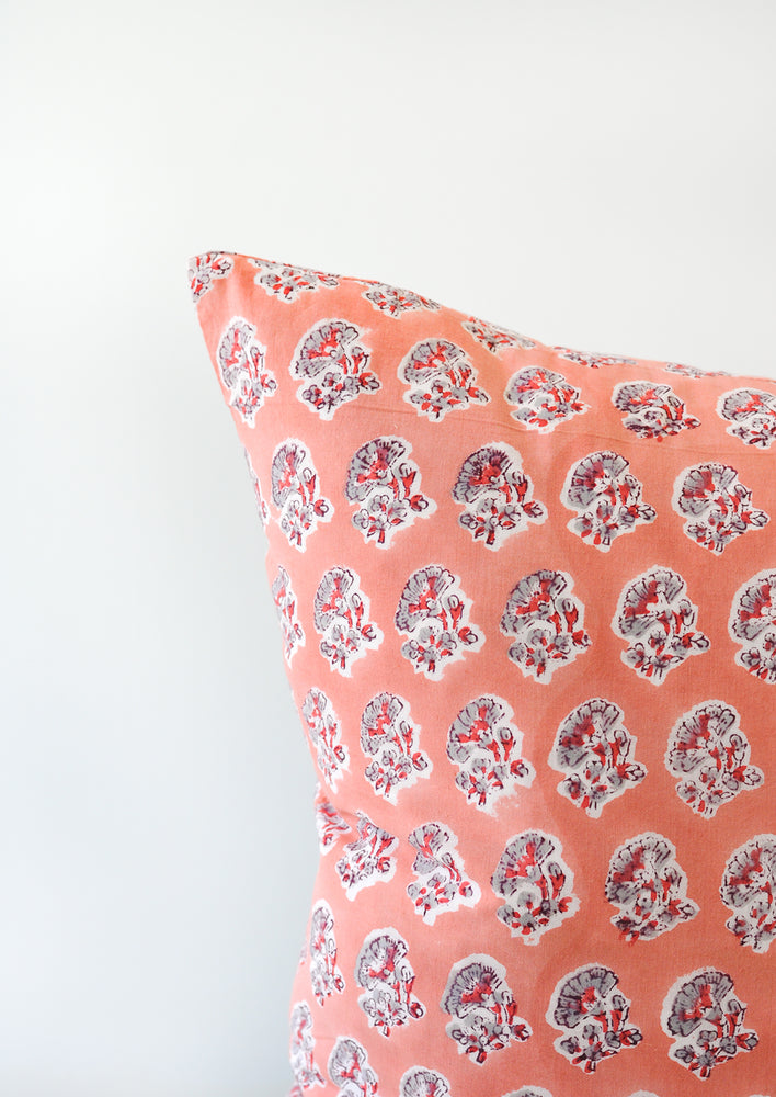 A detail shot of a block printed pillow with a pink, grey, and red floral design.