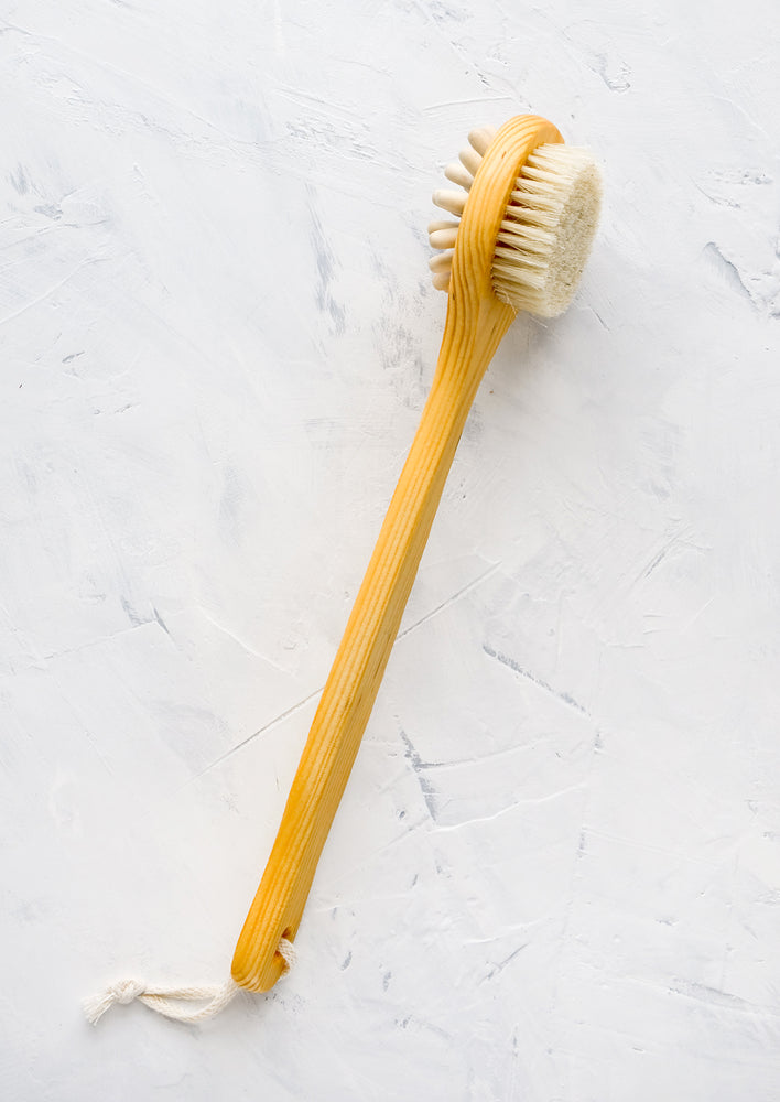 Long-handled cedar brush for using in the shower, featuring a brush side and a massager side.