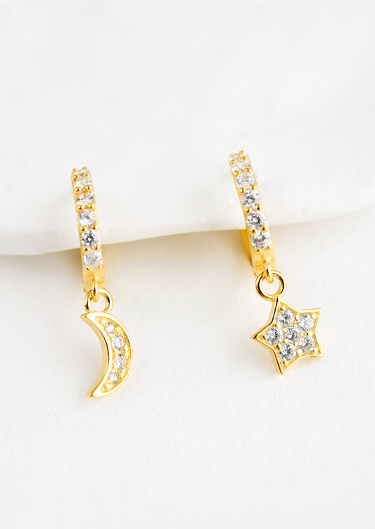 A pair of gold earrings in shape of moon and star with clear crystals.