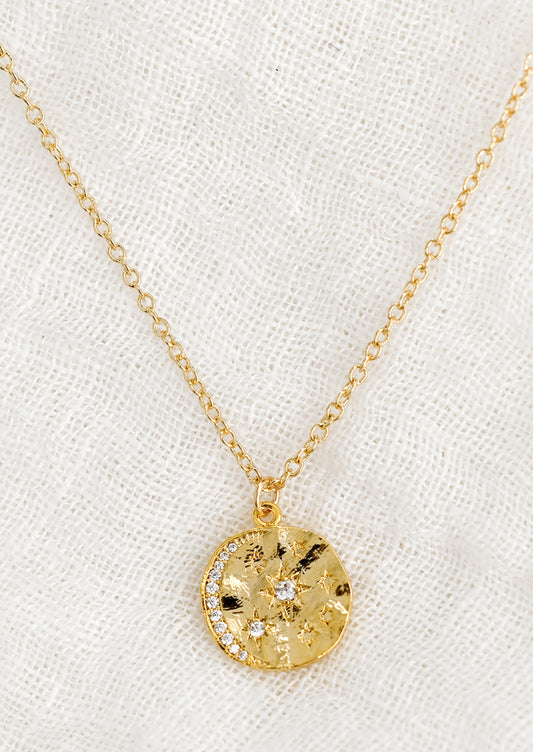 A round pendant necklace with moon and star crystal design.