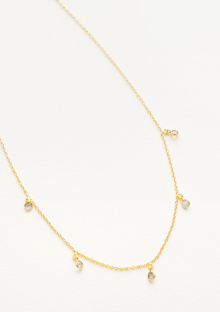 Yellow gold chain necklace with 5 small dangling green gemstones.