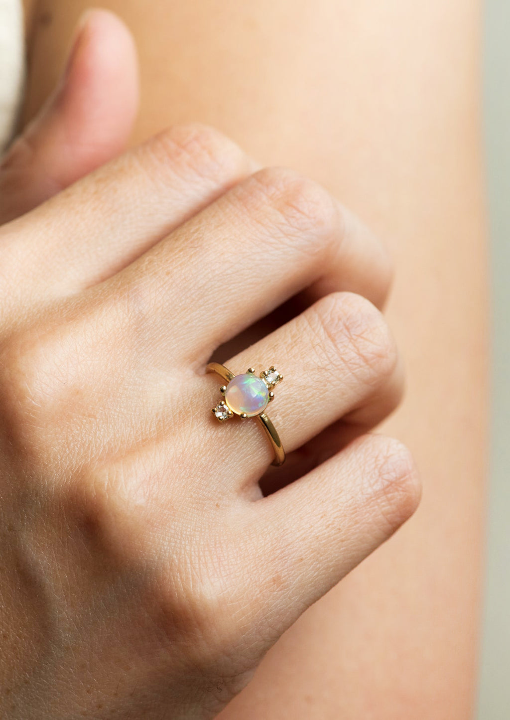 3: A gold ring with large center opal stone and two small white topaz stones.