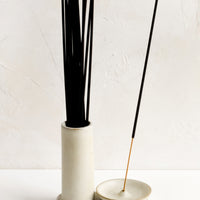 2: A tan ceramic incense holder with stand and incense holder, holding incense sticks.