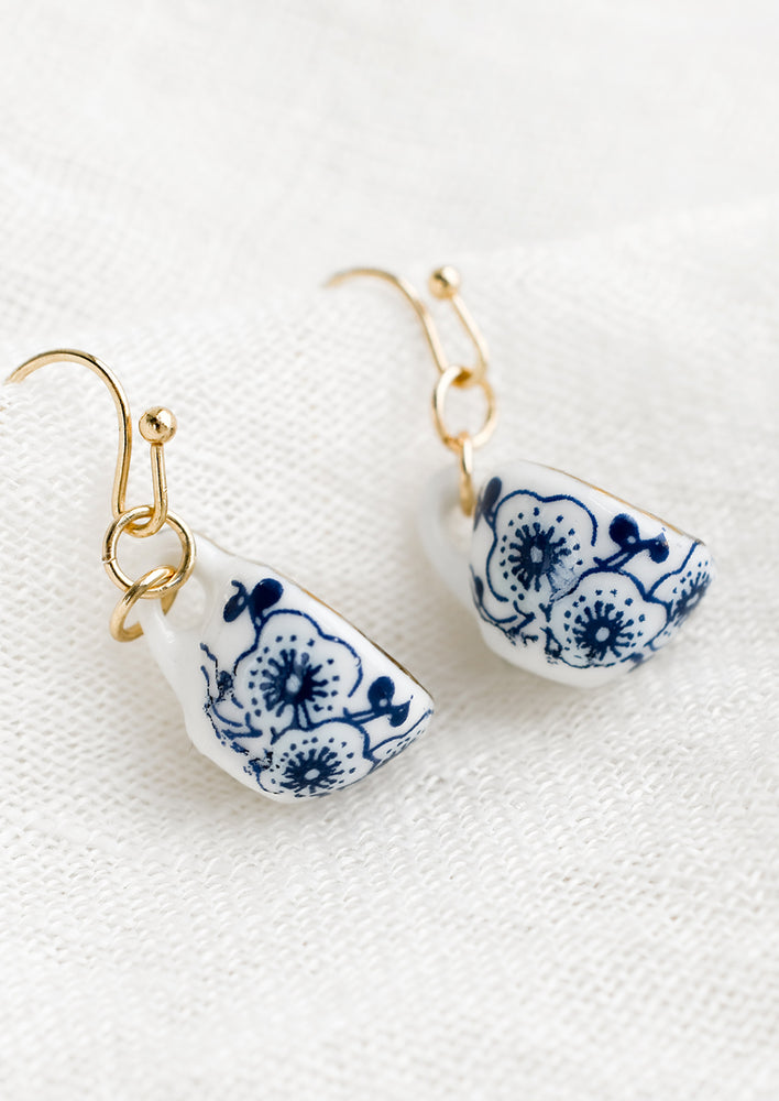 A pair of teacup shaped earrings with blue floral print.