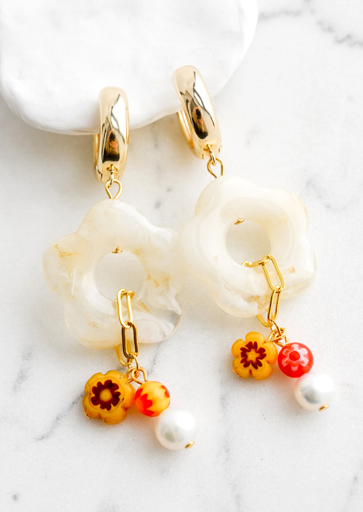 A pair of earrings with chunky gold hoop base and resin and glass flower detailing.