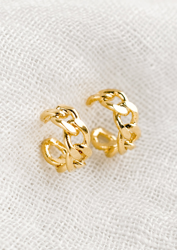 A pair of small gold hoop earrings with chainlink appearance.