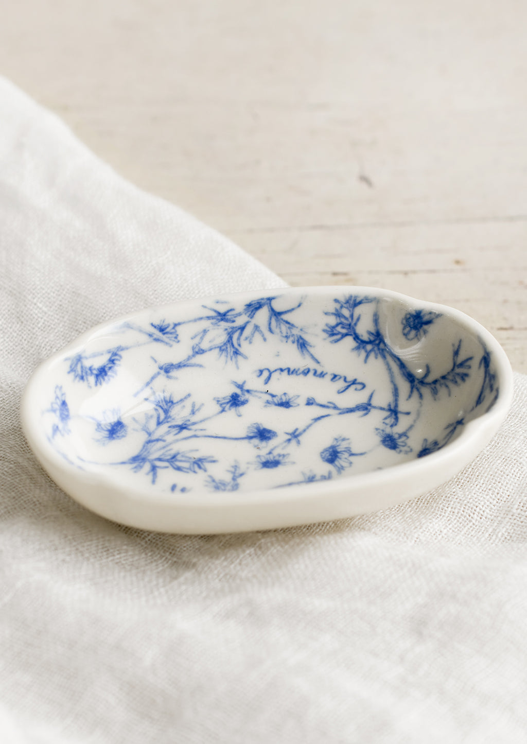 1: A small oval shaped dish in white with blue floral pattern.