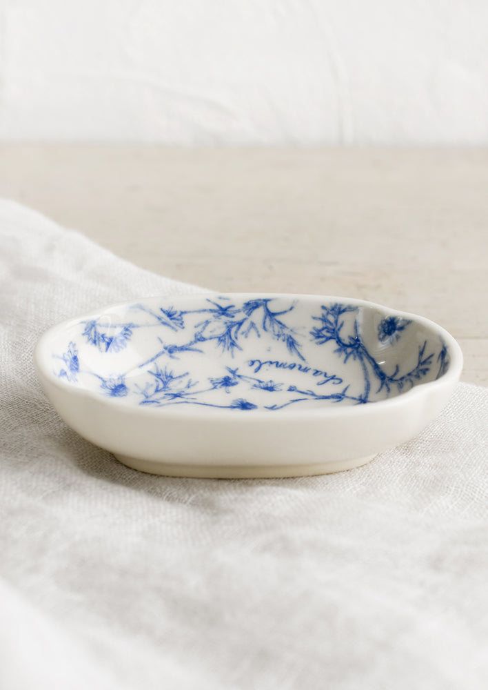 A small oval shaped dish in white with blue floral pattern.