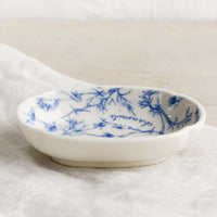2: A small oval shaped dish in white with blue floral pattern.