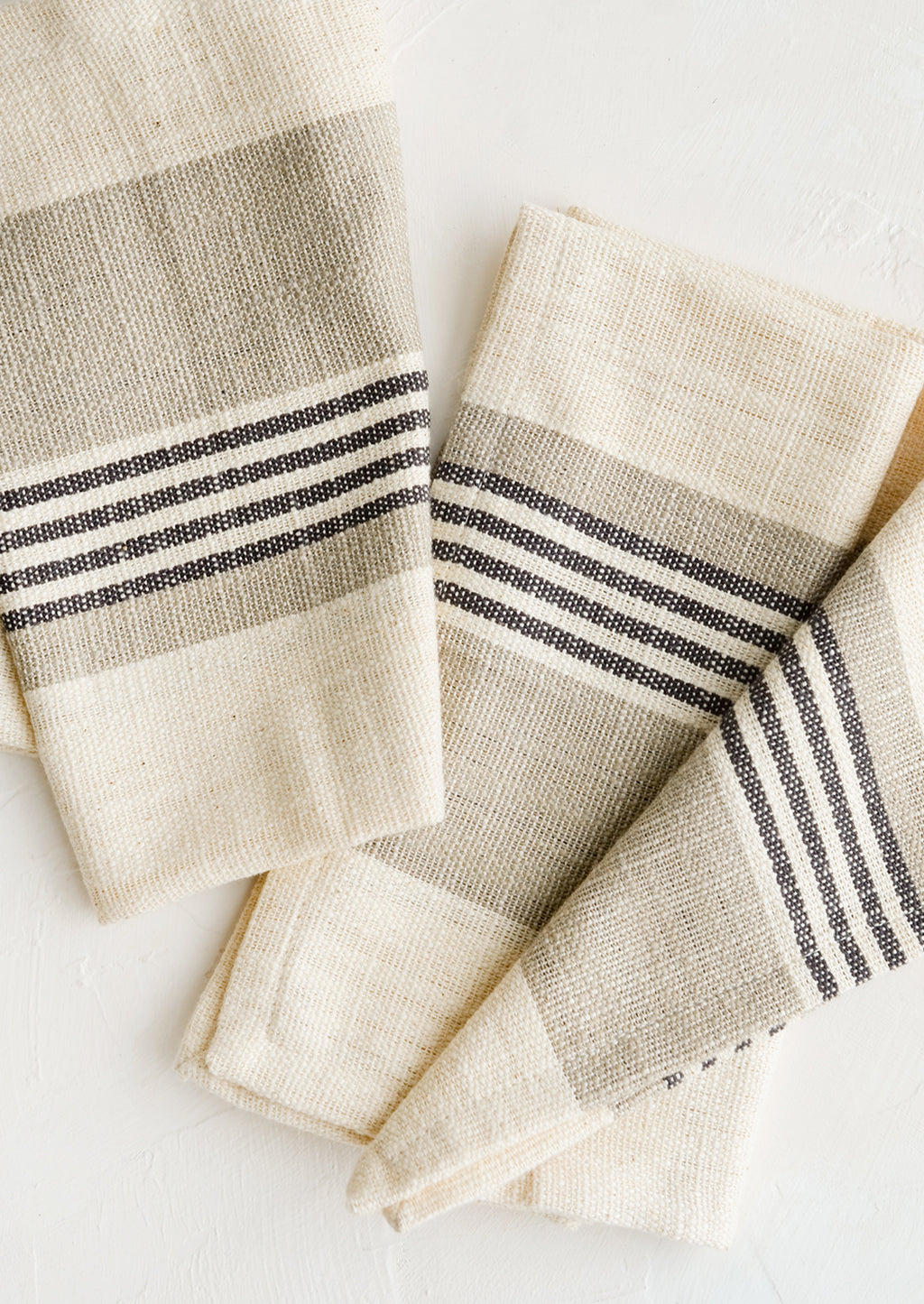 Tan / Black Stripe: A pair of folded napkins in ivory with black and tan striped band across middle.