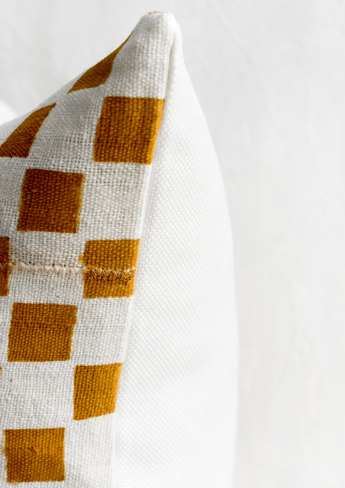 A checkered throw pillow with white linen back.