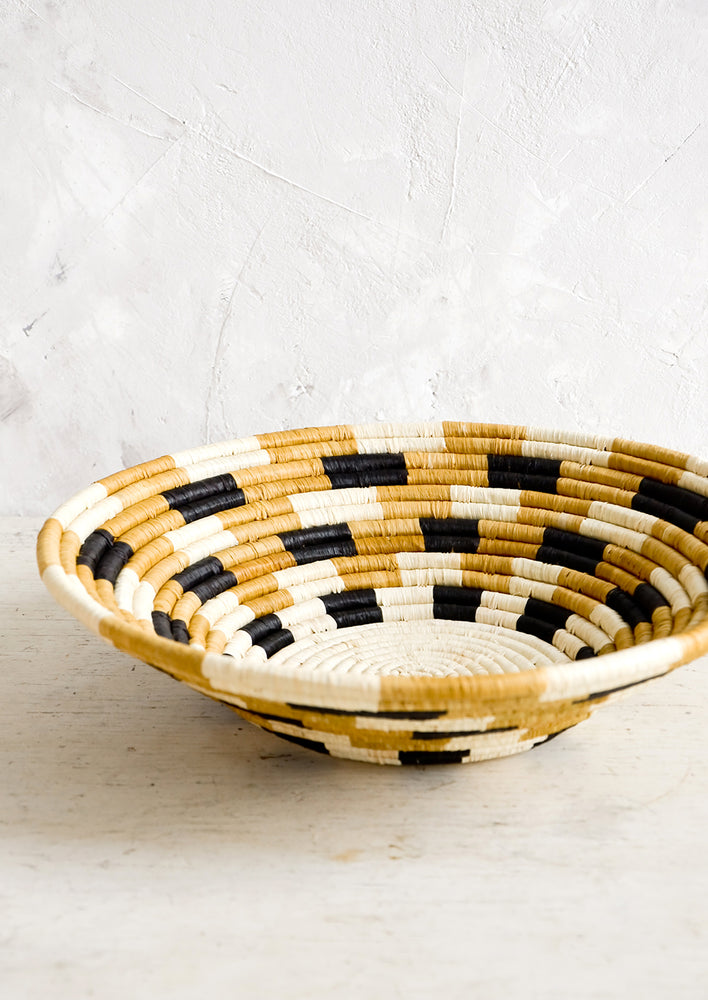 3: Round, shallow bowl made from woven raffia in checkered pattern and neutral palette