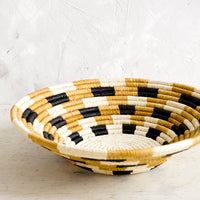 3: Round, shallow bowl made from woven raffia in checkered pattern and neutral palette