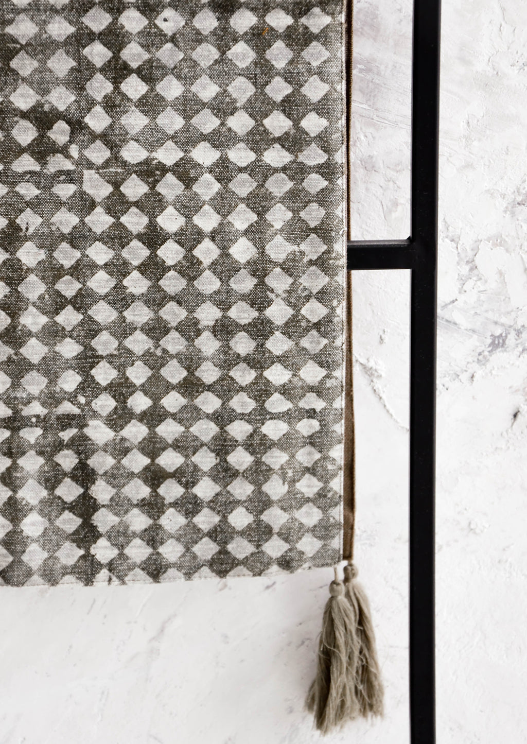 2: Table runner textile in distressed dark grey with white stamped diamond pattern, grey tassels at corners.