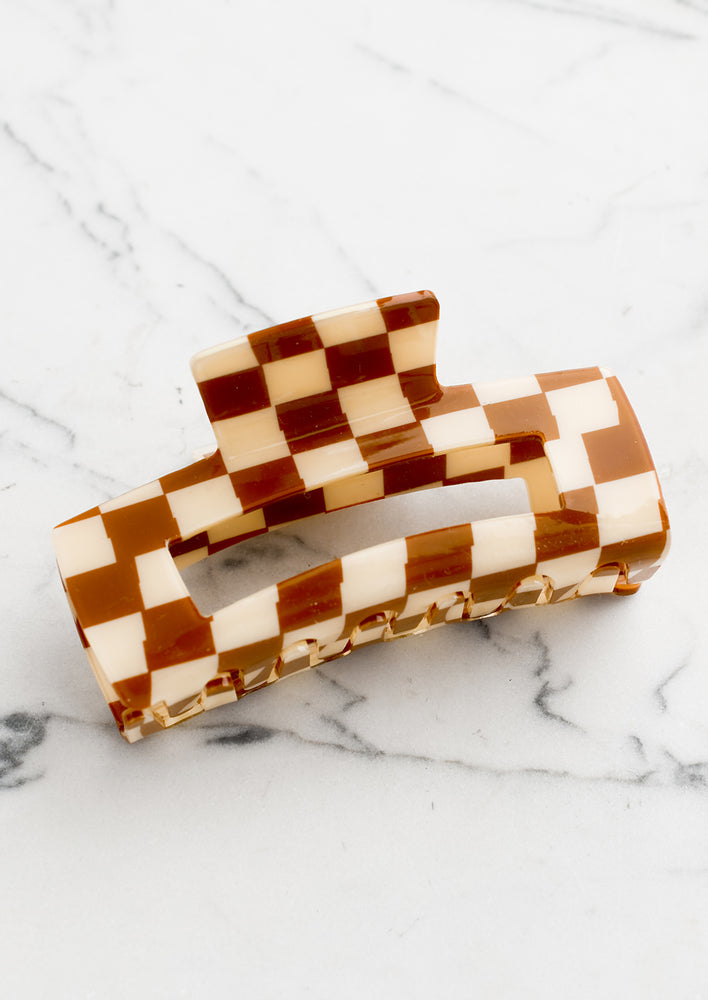 A checker print hair claw in caramel brown and ivory.
