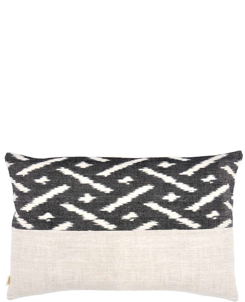 Rectangular throw pillow with black and white ikat patterned top half and natural linen bottom half 