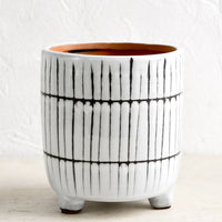 2: A tripod footed ceramic planter in black and white stripe pattern.