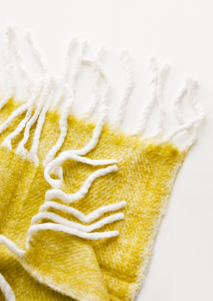 Plush and wooly yellow throw blanket with exaggerated fringe trim in ivory