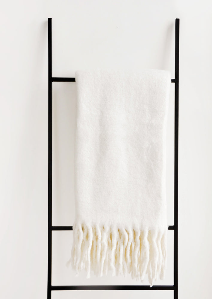 Plush and wooly white throw blanket with exaggerated fringe trim