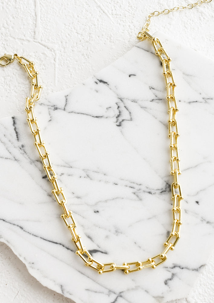 A gold chainlink choker necklace with adjustable lobster clasp closure.