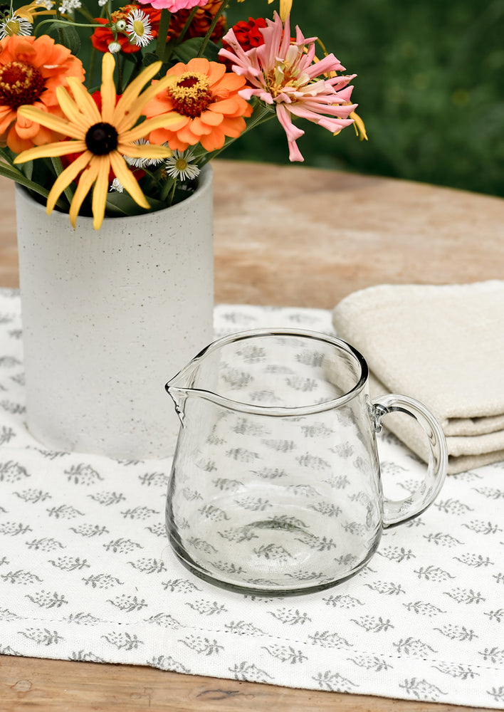 A small clear glass pitcher on a table.