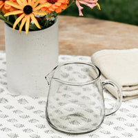 Large / 30 oz: A small clear glass pitcher on a table.