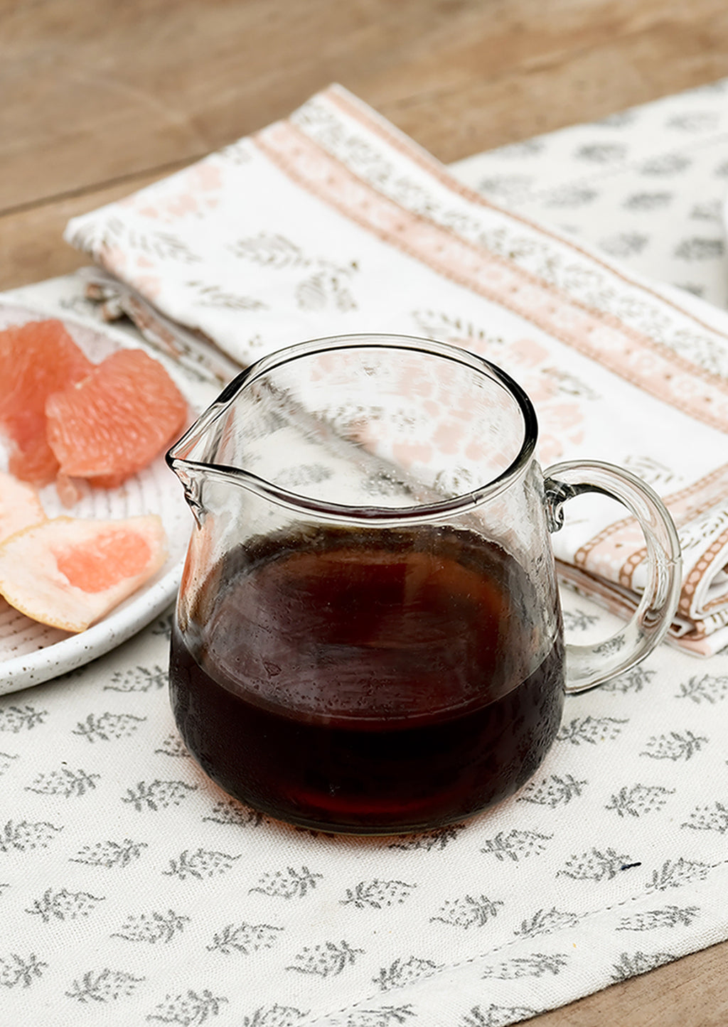 Small / 16 oz: A small glass pitcher on a table, filled with maple syrup.