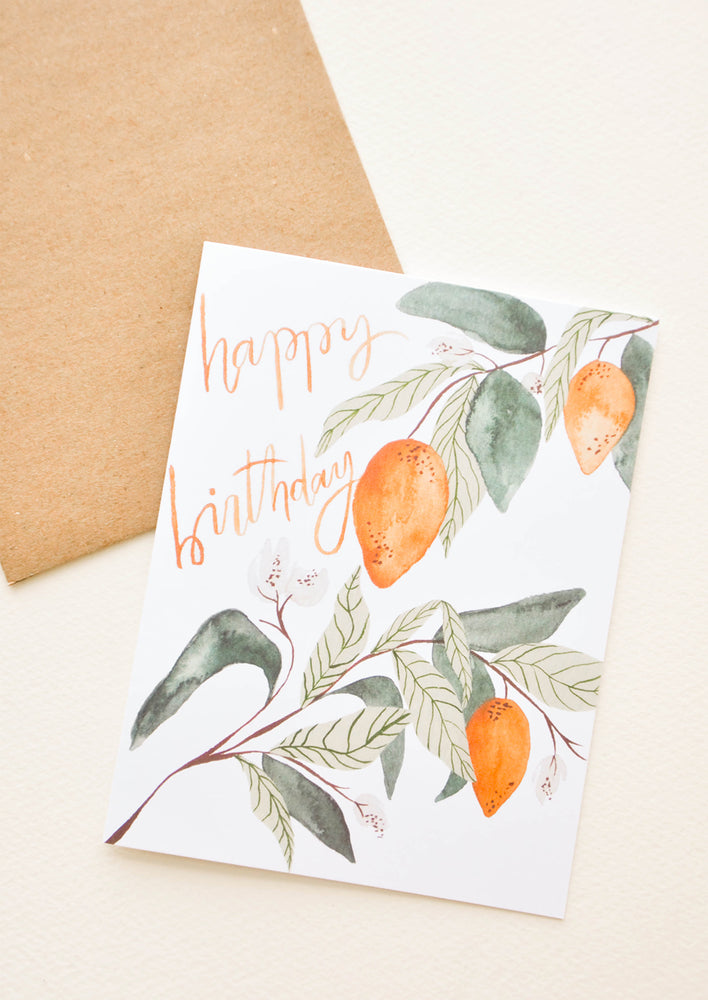 1: White notecard with citrus fruit and leaves decoration and the text "happy birthday" with brown envelope.