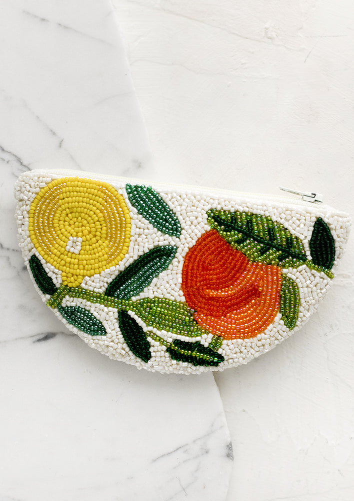 A crescent shaped beaded coin pouch with lemons and oranges pattern.
