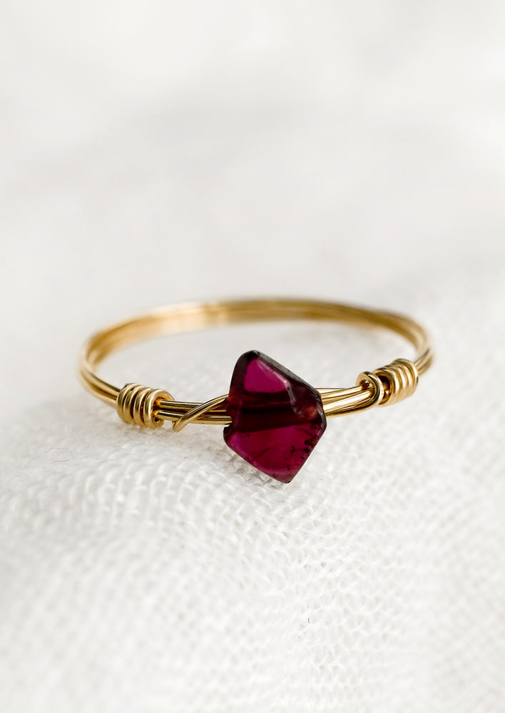 A gold wire wrap ring with diamond-shaped garnet stone.