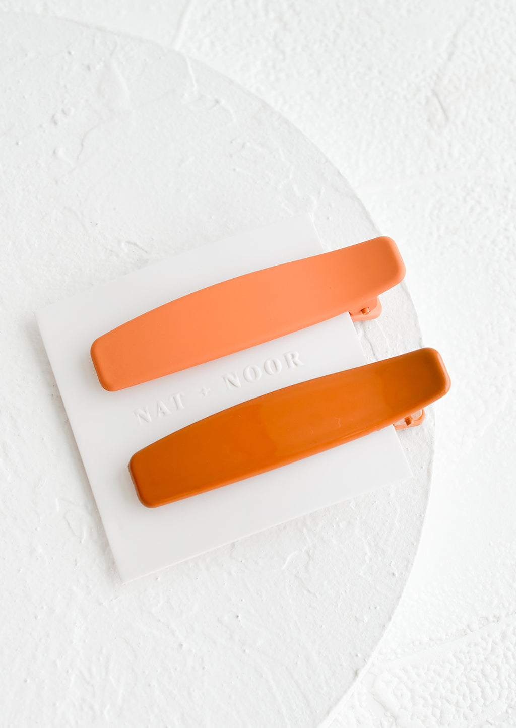 Peach / Terracota: A pair of hair clips with one terracotta and one peach.