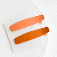 Peach / Terracota: A pair of hair clips with one terracotta and one peach.