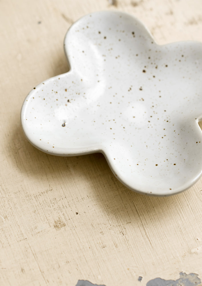 A clover shaped little dish in speckled white ceramic.