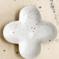 1: A clover shaped little dish in speckled white ceramic.