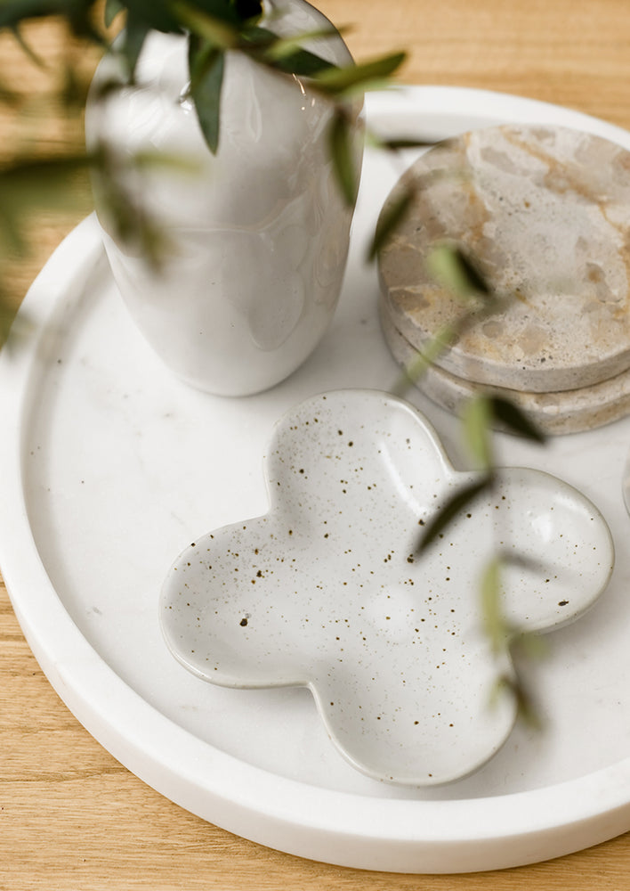 A clover shaped little dish in speckled white ceramic.