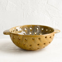 3: A round brown ceramic berry colander bowl.