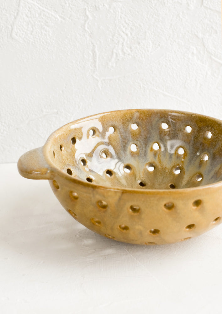 A round brown ceramic berry colander bowl.