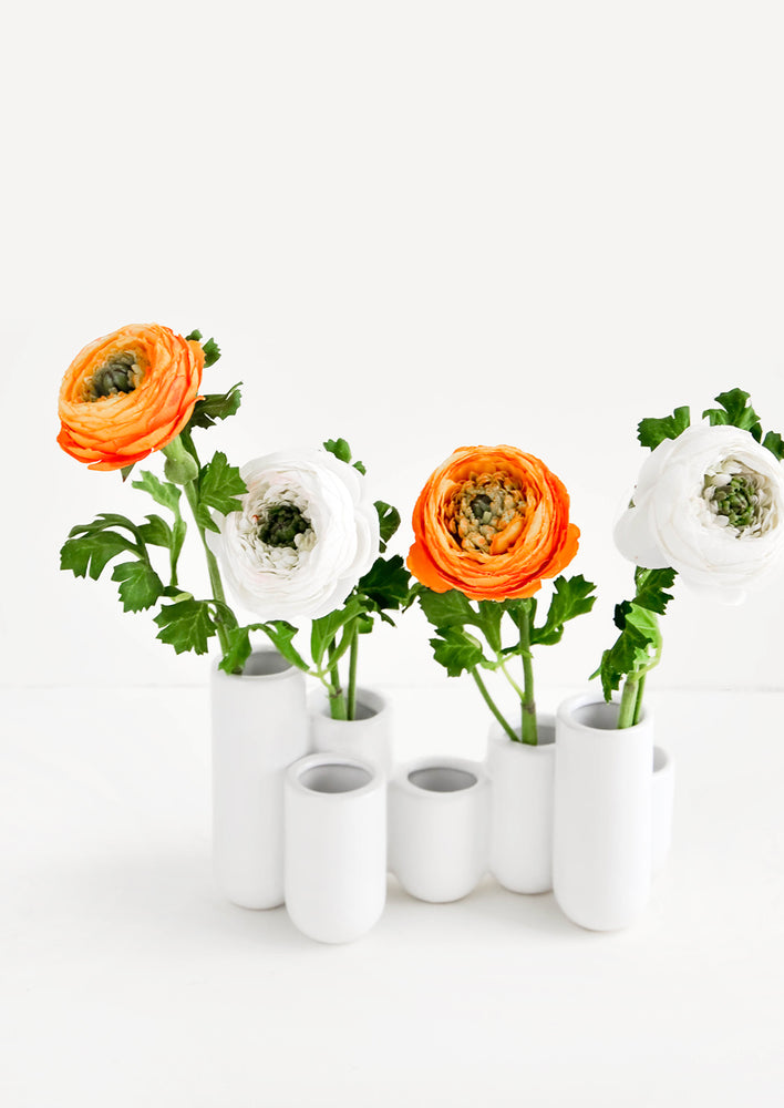 1: Multiple stem vase made of white ceramic vials in varying heights, clustered and fused together. Displayed with ranunculus flowers.